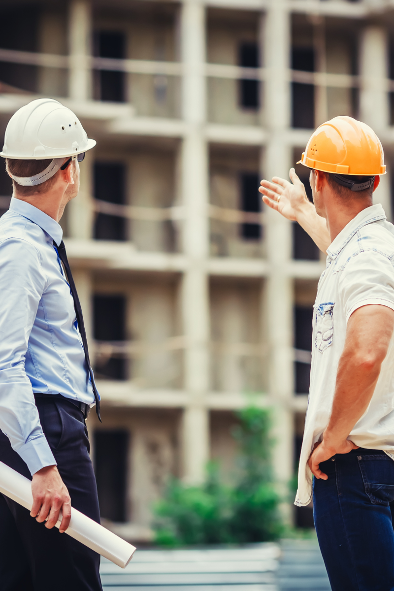 Dois engenheiros de capacete observando um prédio em construção